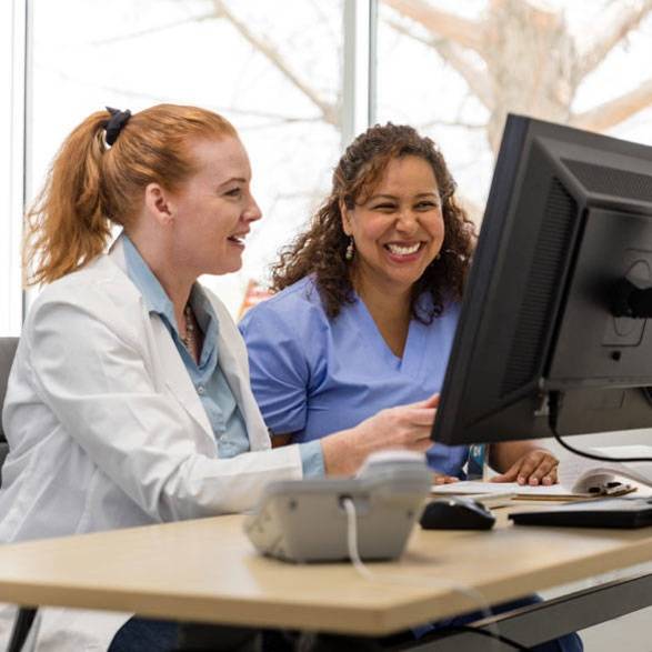 Pflegefachkräfte sitzen vor PC