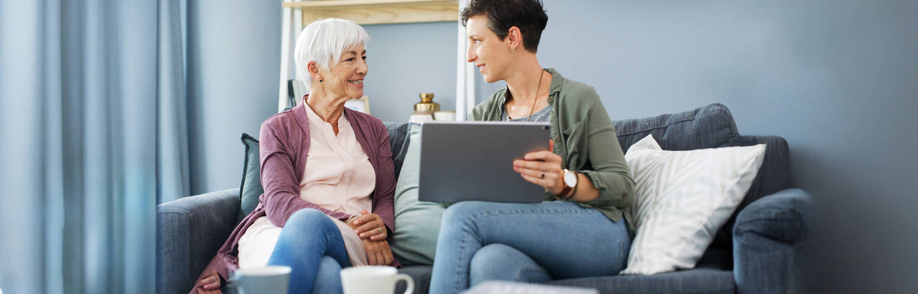 Außendienst mit Laptop berät Patientin zu Hause auf dem Sofa