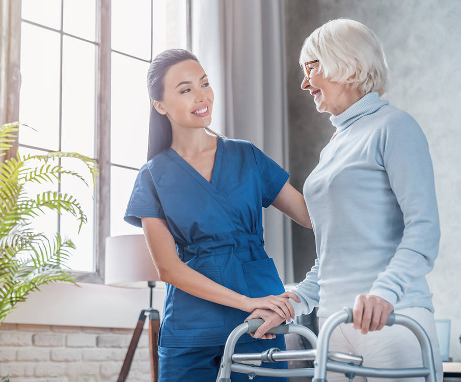 Pflegerin hilft alter Frau mit Gehhilfe
